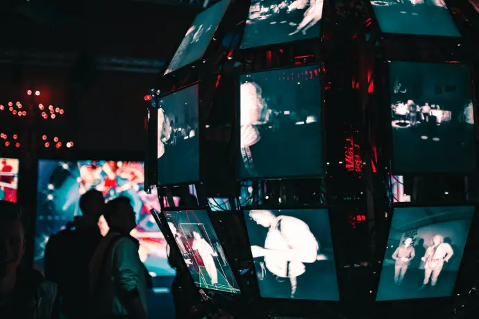 a group of people standing around a display of video screens, IT